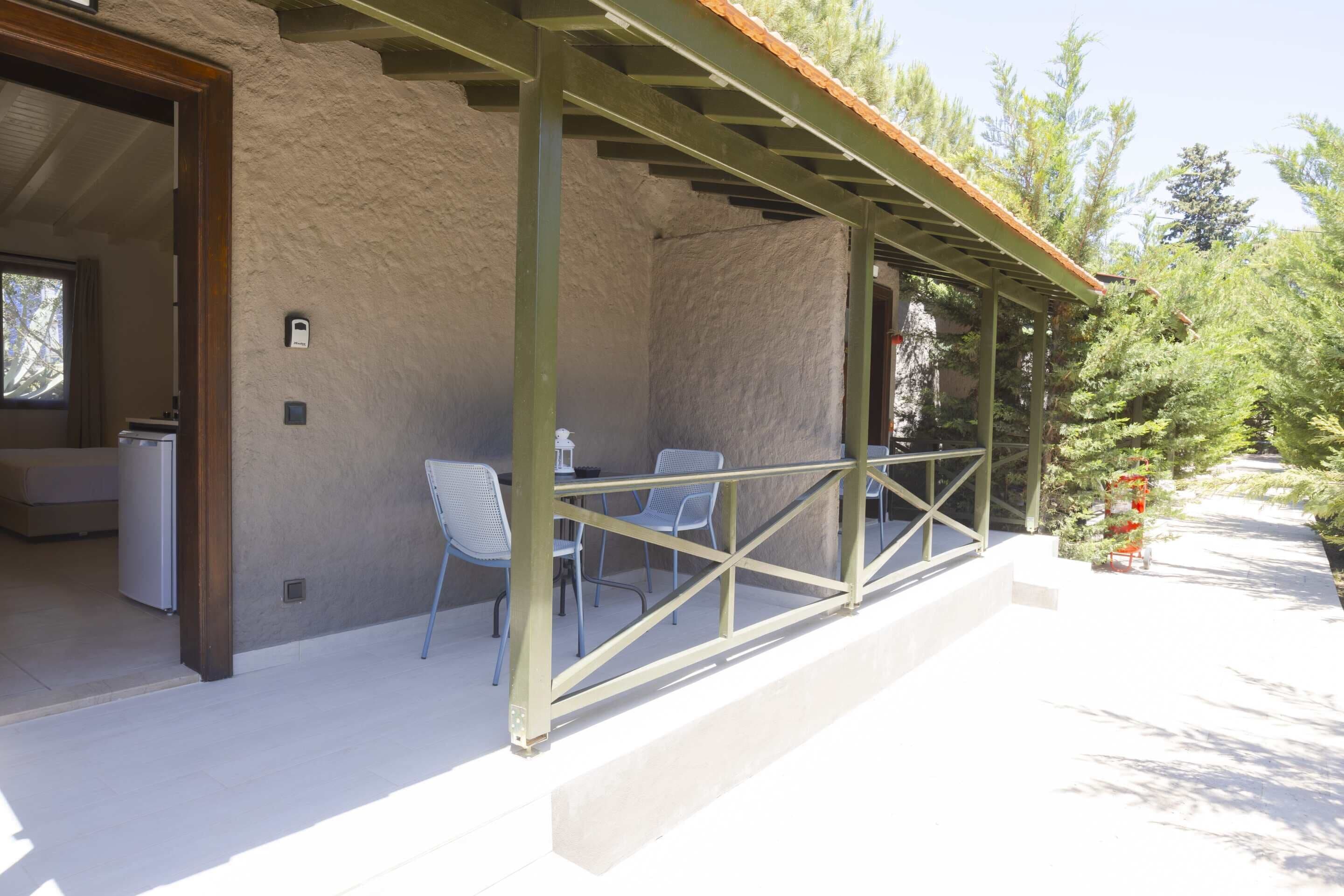 An outdoor patio with a covered seating area, a refrigerator, and a small Christmas tree.