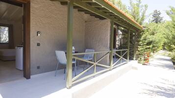 An outdoor patio with a covered seating area, a refrigerator, and a small Christmas tree.