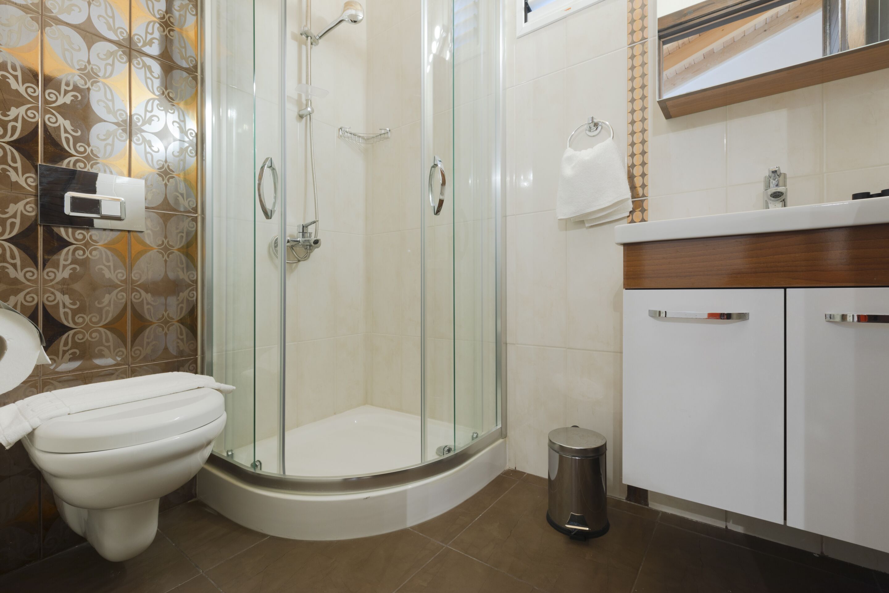 A modern bathroom with a glass-enclosed shower, a toilet, and a sink with a wooden countertop.