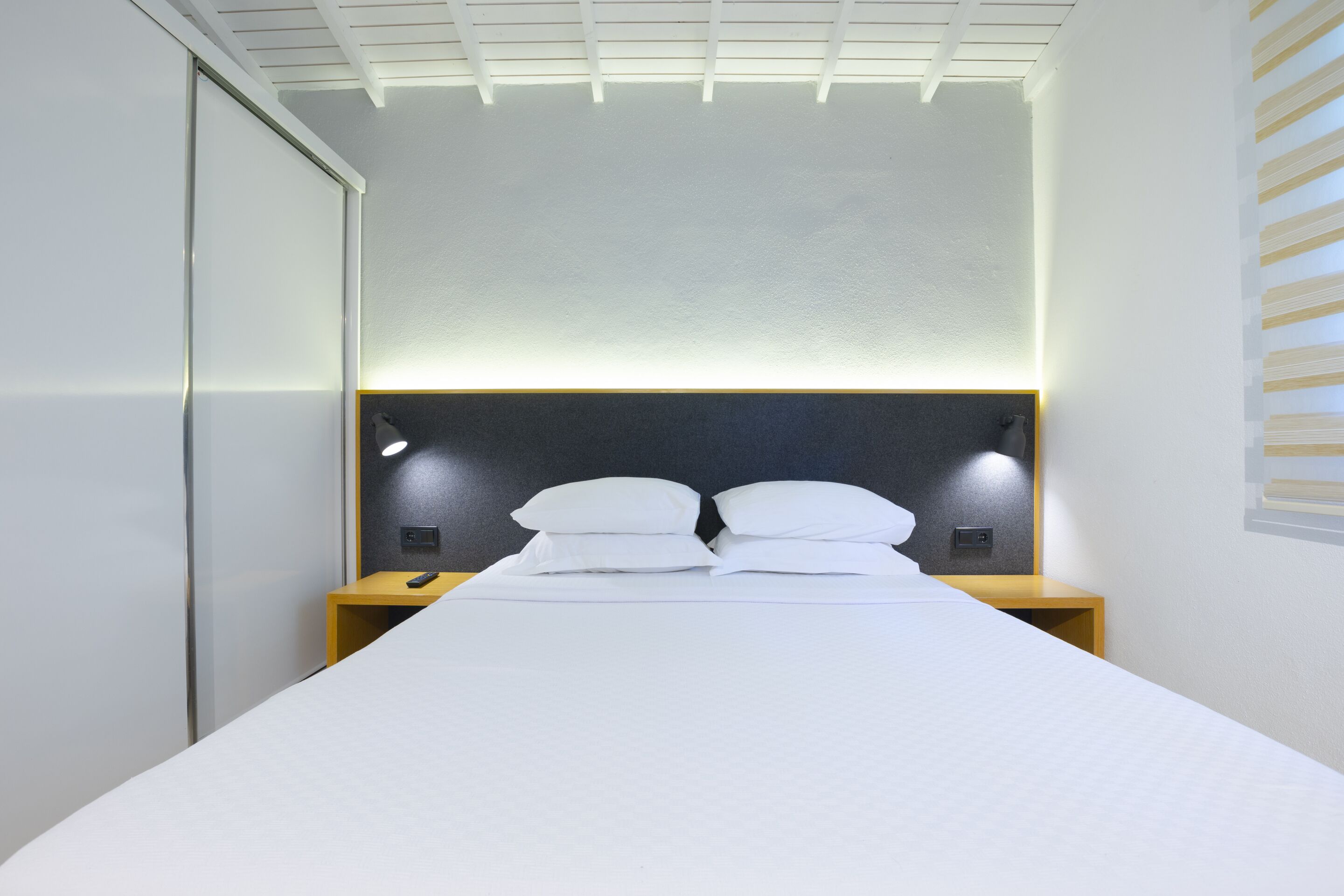 A modern hotel room with a bed, bedside lamps, and a headboard.