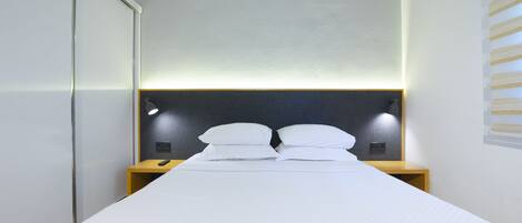 A modern hotel room with a bed, bedside lamps, and a headboard.
