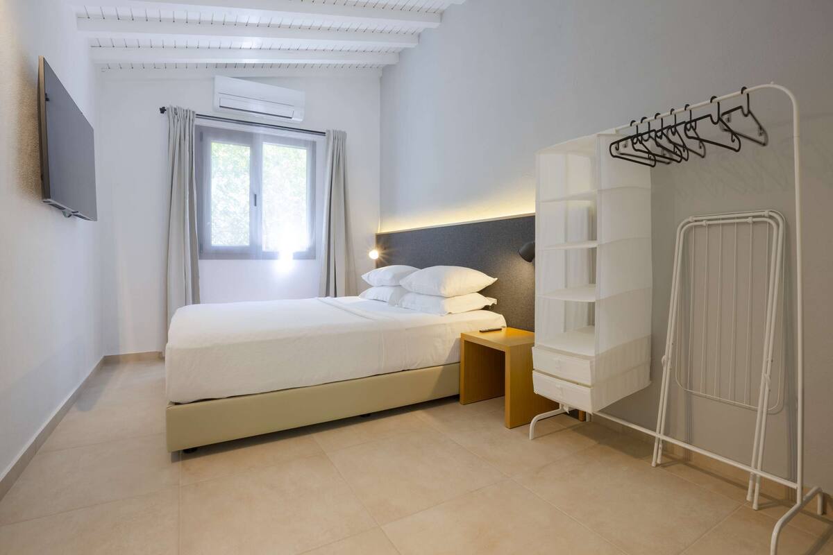 Un dormitorio moderno con cama, mesita de noche y armario empotrado con un tendedero.