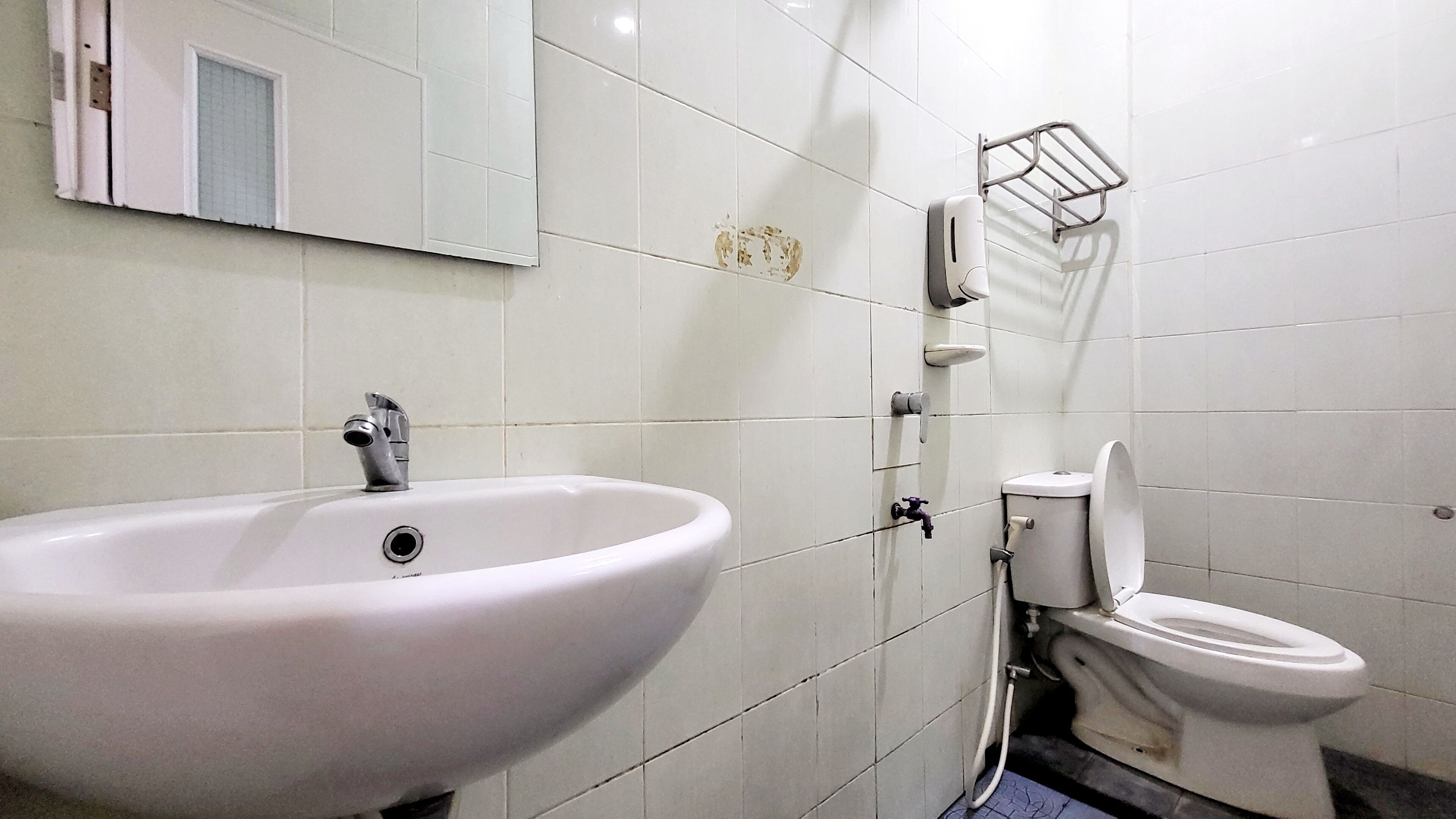 A bathroom with a white sink, toilet, and a mirror.