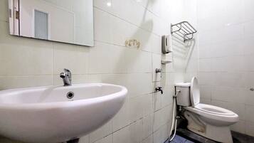 A bathroom with a white sink, toilet, and a mirror.