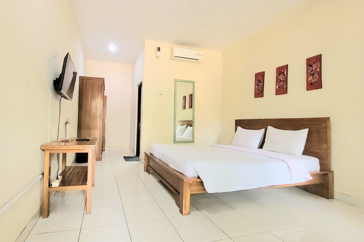 A hotel room with a bed, a desk, a TV, and a mirror.