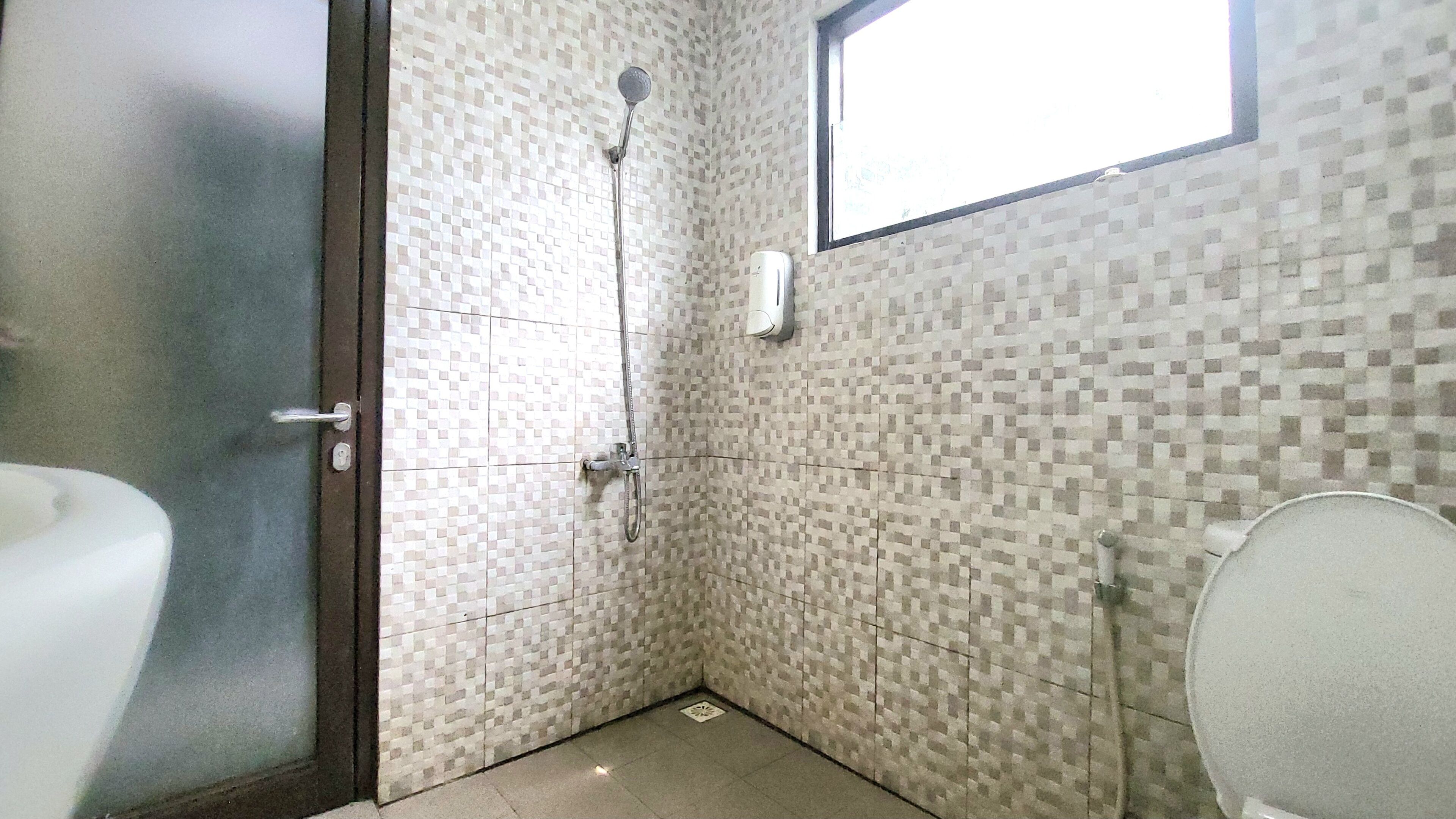 A bathroom with a shower, toilet, and a window.