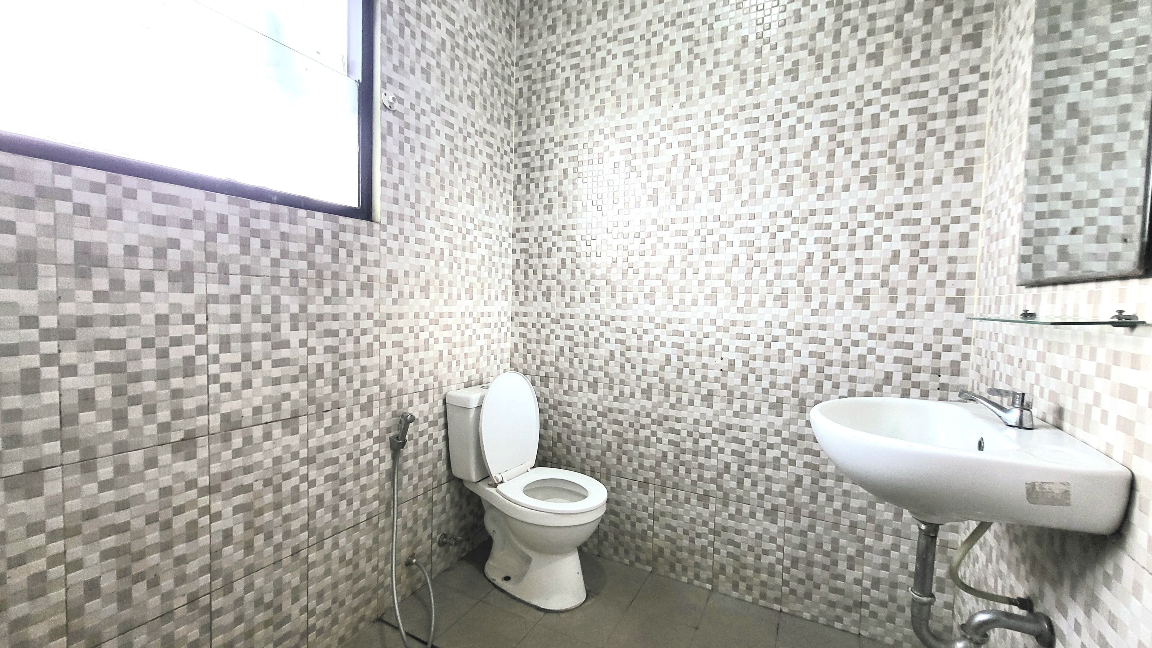 A bathroom with a toilet and sink, tiled walls, and a window.