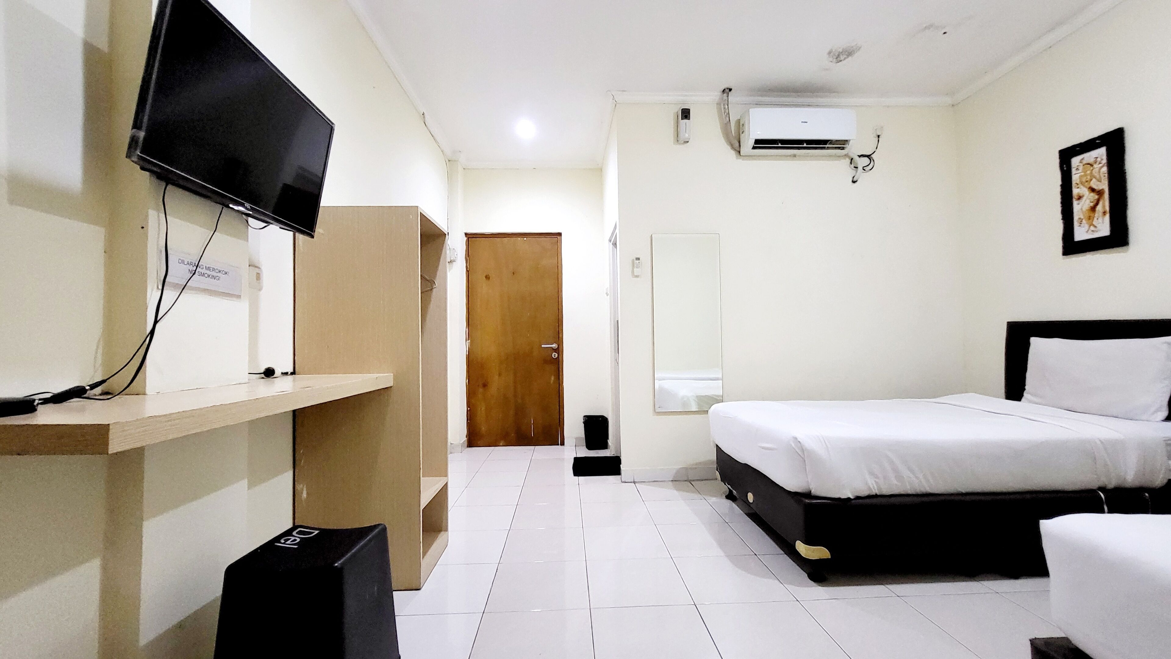 A hotel room with a bed, a TV, an air conditioner, a desk, and a wardrobe.