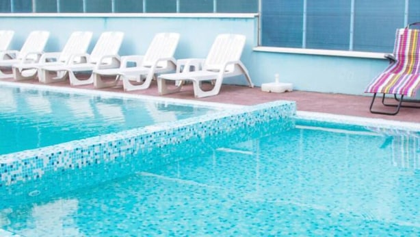 Una piscina con sillas de descanso blancas y una toalla colorida a rayas.