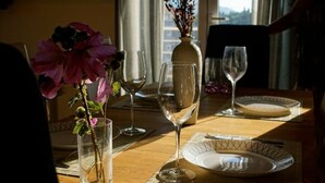 Una mesa de comedor con un florero, copas de vino y platos.