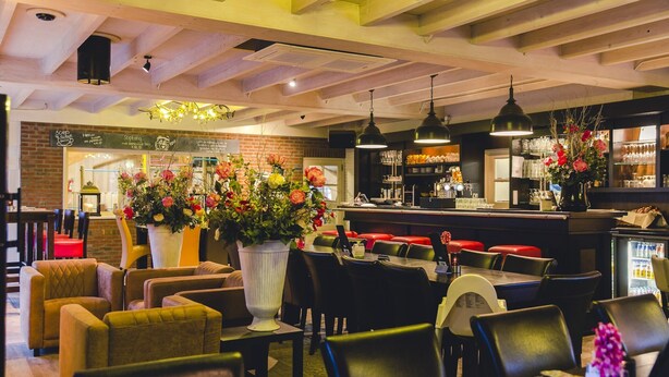 L’intérieur d’un restaurant avec des poutres en bois, des suspensions et un mur en briques.