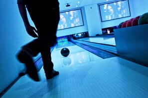 A bowling alley with lanes, a bowling ball, and a person in motion. - Starlit Tent Lodge Escape (Zuna)