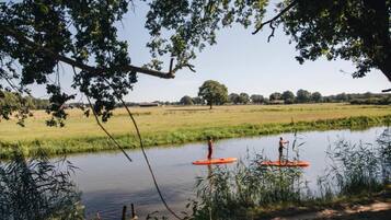Ein Fluss, auf dem zwei Personen auf einem roten Stand-Up-Paddleboard paddeln.