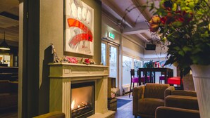 A cozy lobby with a fireplace, comfortable seating, and a large window offering a view of the outdoors. - Holiday Home in Overijssel with Garden Terrace (Zuna)