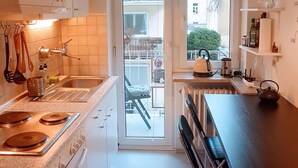 Une cuisine compacte équipée d’une cuisinière, d’un évier et d’un coin repas, offrant une vue sur le balcon extérieur.