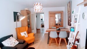 Un salon moderne comprenant un canapé, une table à manger avec des chaises, une lampe et un luminaire décoratif au plafond.