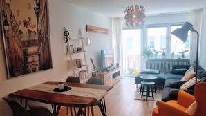 Un salon comprenant un coin repas, un canapé, un téléviseur et une bibliothèque.