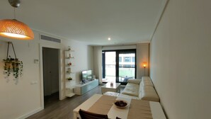 A modern living room with a dining area, a TV, and a balcony with a view. - NON STRESS First Level (Alboraya)