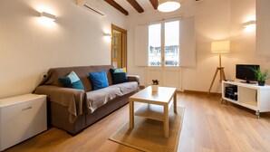 A modern living room with a sofa, a coffee table, a lamp, and a TV on a stand. - Fantastic and Bright Apartment in the Heart of Gothic area 10 min from the beach (Barcelona)