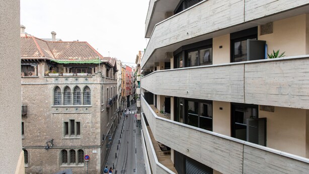 A narrow street flanked by historic and modern buildings, with a clear view of the street and adjacent buildings. - Fantastic and Bright Apartment in the Heart of Gothic area 10 min from the beach (Barcelona)