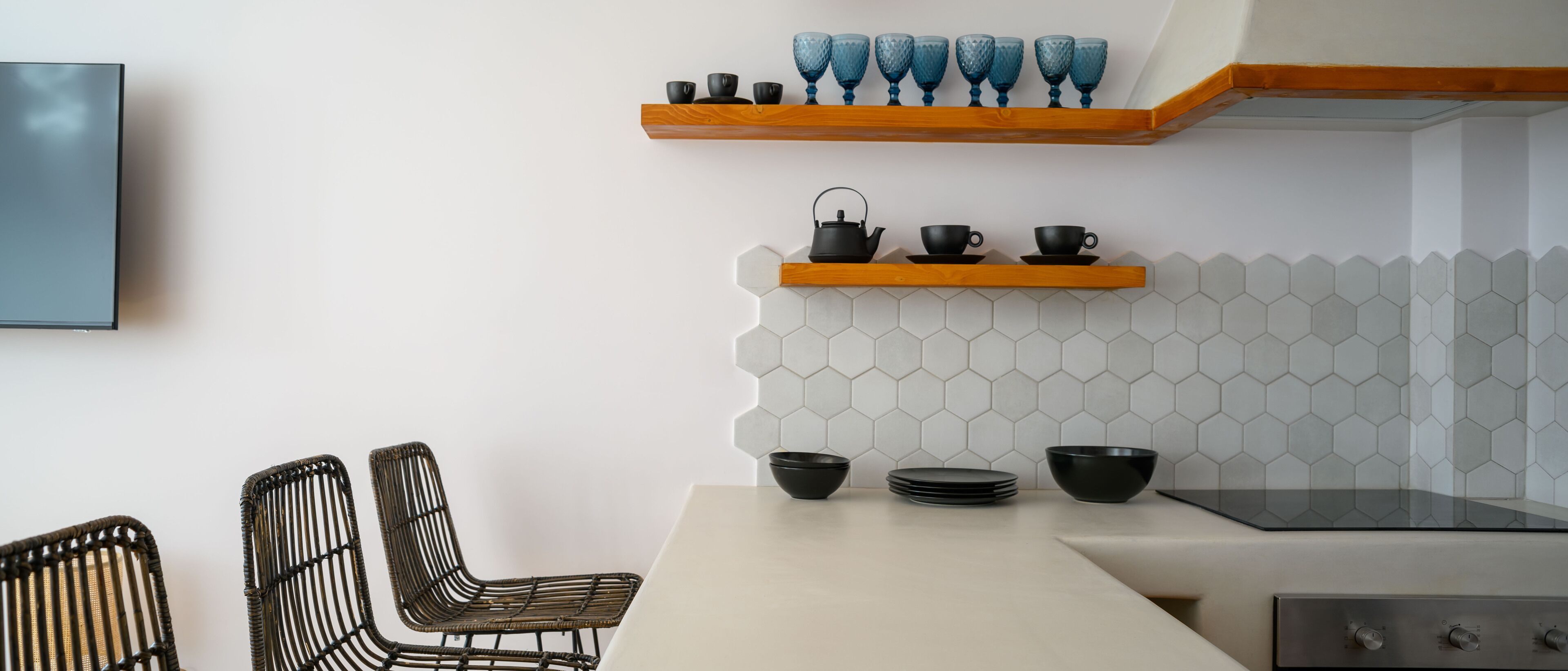 Una cocina moderna con dos sillas de mimbre, una mesa de comedor, una estufa y estantes con utensilios de cocina.