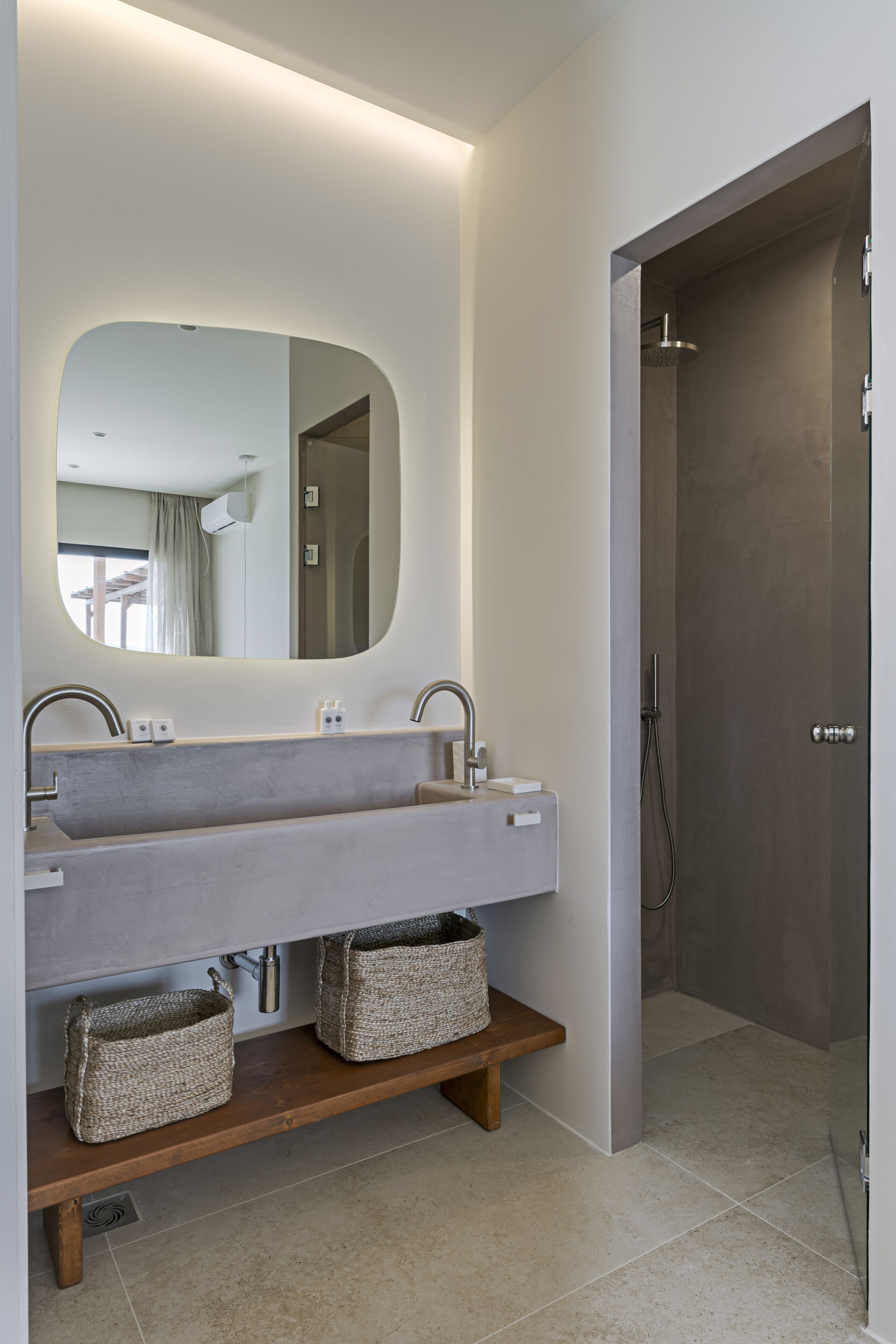 A modern bathroom with a large mirror, two sinks, and a shower.