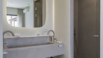 A modern bathroom with a large mirror, two sinks, and a shower.