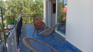 A balcony with wicker chairs, a potted plant, and a view of trees and buildings. - Villa close to the sea with terrace and free parking  (Licinella-Torre di Paestum)