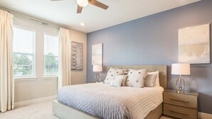 Una camera da letto con un letto, due comodini, una ventola a soffitto e opere d'arte alle pareti.