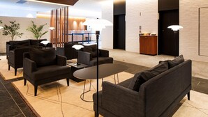 Un hall d’entrée moderne avec des canapés sombres, une table ronde et un comptoir d’accueil.