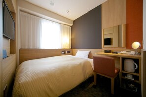 Habitación de hotel con cama, escritorio con silla, televisor, espejo y ventana con cortinas.