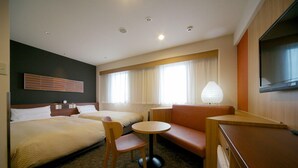 Une chambre d’hôtel avec deux lits, un canapé, une petite table, une chaise, une télévision et une lampe.