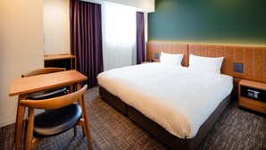 Une chambre d’hôtel avec un grand lit, un bureau avec une chaise et une table de chevet.