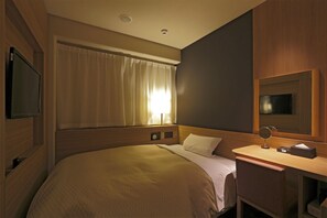 A hotel room with a bed, a desk, a mirror, a TV, and a window with curtains.