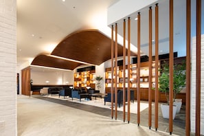 Un vestíbulo moderno con techo de madera curvada, zona de estar y mostrador de recepción.