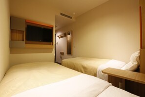 Habitación de hotel con dos camas, una mesita, un espejo y una ventana con persianas.