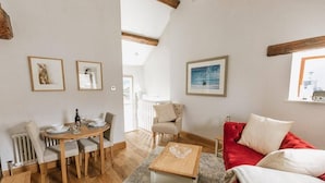 Un salon chaleureux avec une table à manger, un canapé rouge et une table basse en bois.