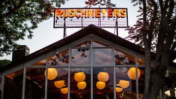 A building with a neon sign reading "RUSCHMEYERS" and large windows with hanging paper lanterns.