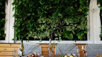 A dining area with a table set for two, a bottle of wine, and a glass of wine on the table.