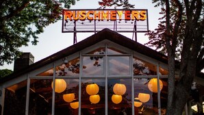 A building with a neon sign reading "RUSCHMEYERS" and large windows with hanging paper lanterns. - Ruschmeyers #17 - Dlx King (Montauk)