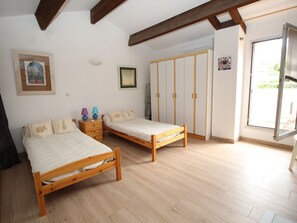 Quarto com duas camas de madeira, um guarda-roupa e uma porta de correr de vidro para uma varanda.