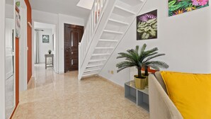 Un interior moderno con una escalera, una planta en maceta y obras de arte en las paredes.