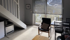 Ein Wohnzimmer mit Treppe, einem Essbereich mit Stühlen und einem großen Fenster mit Blick auf Bäume.