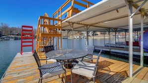 A wooden deck with a covered seating area, a metal table, and chairs.