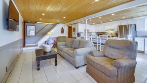 A spacious living area with a wooden ceiling, a sofa, a chair, and a dining table.