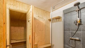 Een houten sauna met een douchehoek.