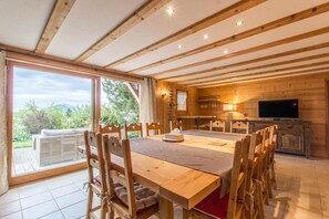 Een houten interieur met een eetgedeelte, een televisie en uitzicht op de omgeving.