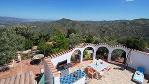 A patio with a grill, outdoor seating, and a view of the surrounding hills.
