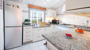 A modern kitchen with white cabinets, granite countertops, a refrigerator, a microwave, and a stove.