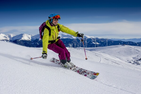 A person skiing on a snowy slope with a clear sky and mountains in the background. - Superior Chalet # 15 with IR-sauna & Whirlpool (Murau)